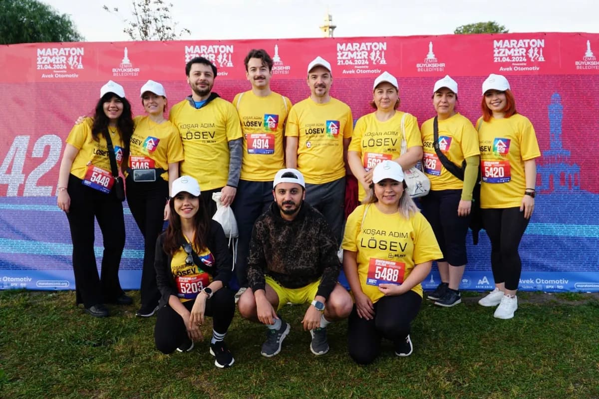 Maratonİzmir 2024 panosu önünde toplu ekip fotoğrafı