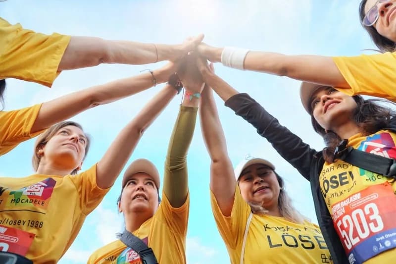 Maratonİzmir 2024'te LÖSEV forması giyen Martı Yazılım ekibi ellerini havada birleştirirken